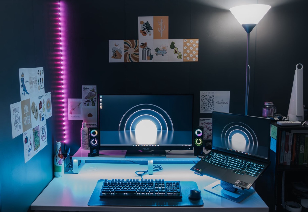 Gaming laptop setup in a German studio with technical notes and a monitor display